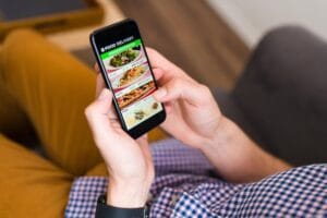 Cliente pedindo comida pelo celular em aplicativo de entrega